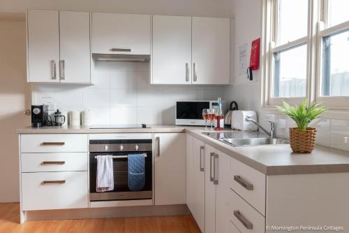 a white kitchen with a sink and a stove at MP Beach Club in Tootgarook