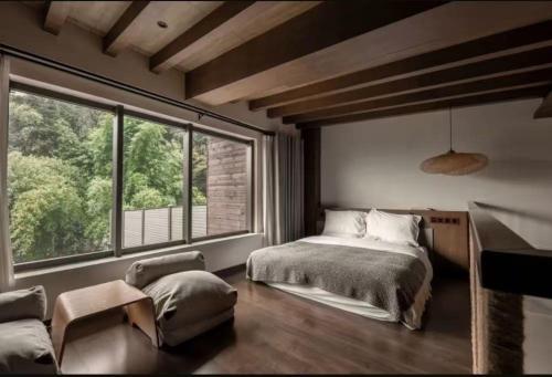 a bedroom with a bed and a large window at 青城山坐忘森林疗愈酒店 in Dujiangyan