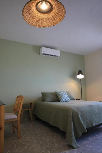 a bedroom with a bed and a lamp and a chair at Mola Mola Rooms in Mérida