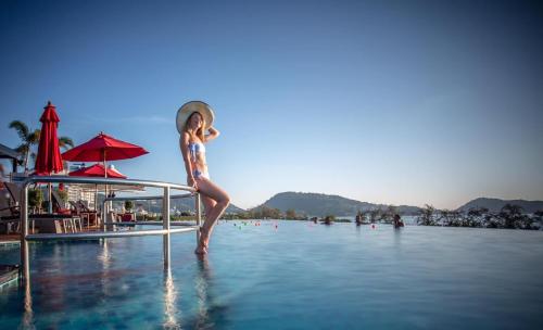 a woman standing on the edge of a pool of water at Beachfront Deluxe BR Infinity Pool Patong Phuket in Patong Beach
