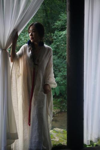 a woman is looking out of a window at 青城山坐忘森林疗愈酒店 in Dujiangyan