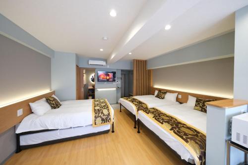 a hotel room with two beds and a television at HOTEL AARON Taisho Ekimae in Osaka
