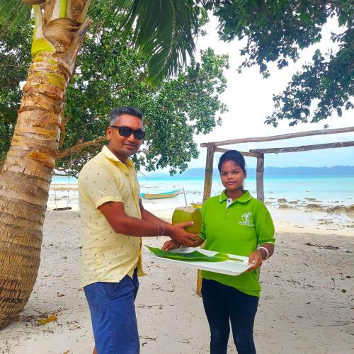 a man and a woman holding a plate on the beach at Lemon Grass Resort & Spa in Havelock Island