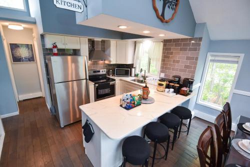 a kitchen with a white island with chairs and a refrigerator at Bool Bear Lodge a pet friendly Pocono Vacation Home in Tobyhanna