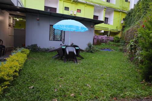 a patio with a table and a blue umbrella at Rijo Villa in Munnar
