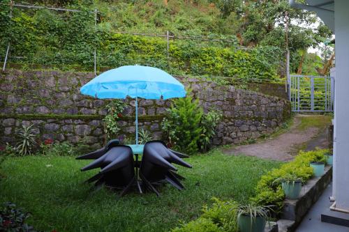 a table and an umbrella in a yard at Rijo Villa in Munnar