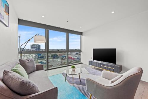 a living room with a couch and a flat screen tv at Trafalgar Lane Apartments by CLLIX in Brisbane