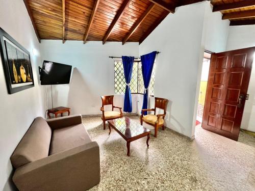 a living room with a couch and chairs and a tv at CASA FAMILAR frente al parque in Buga