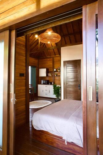 a bedroom with a large bed and a kitchen at Sun and Moon Bungalow Village in Uluwatu