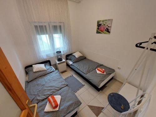 a small room with two beds and a window at Zseki apartman in Hajdúszoboszló