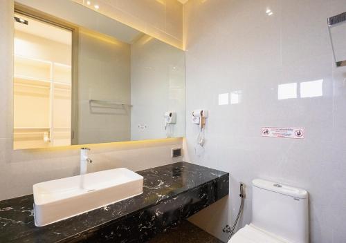 a bathroom with a sink and a toilet and a mirror at Sirintara pool villa in San Sai