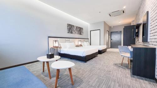 a hotel room with a bed and two tables at Fives Hotel DNP in Johor Bahru
