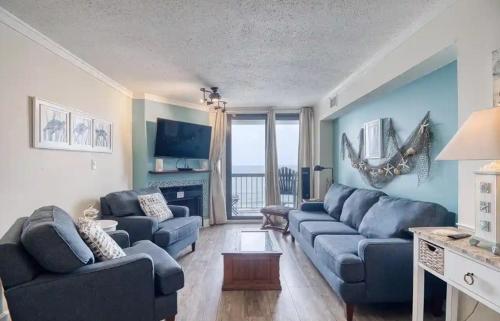 a living room with blue couches and a fireplace at Oceanfront Waterpointe 1 Unit 803 3 bedroom 2 bath Balcony Pools in North Myrtle Beach