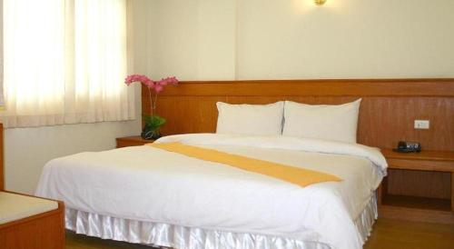 a bedroom with a large bed with white sheets at Loei Orchid Hotel in Loei