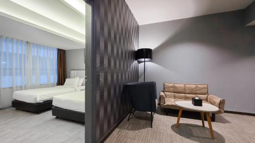 a hotel room with a bed and a chair and a table at Fives Hotel DNP in Johor Bahru