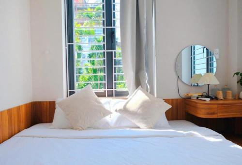 a bed with white pillows in a bedroom with a window at Adora Homestay Hue in Hue