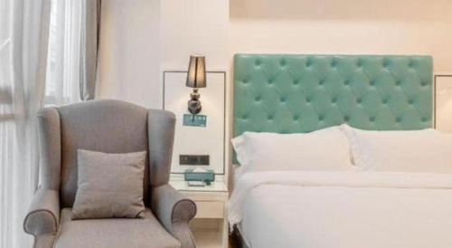 a bedroom with a bed and a chair at Xana Lite Anqing Yuexi Swan Squre Branch in Yuexi