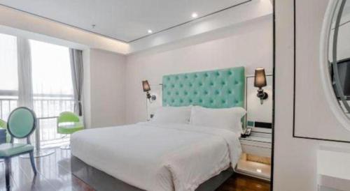 a bedroom with a large white bed and a green headboard at Xana Lite Anqing Yuexi Swan Squre Branch in Yuexi
