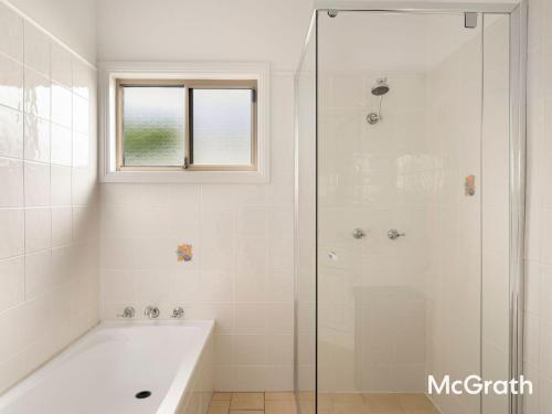 Mango Tree Cottage في ساوتيل: حمام أبيض مع حوض استحمام ونافذة