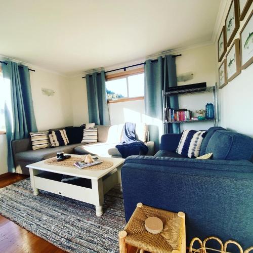 a living room with a blue couch and a coffee table at Spindrift Falmouth, adventurers coastal haven in Falmouth