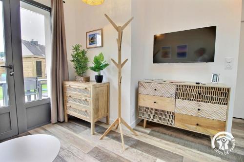 a living room with a tv and a dresser at La source in Plouhinec