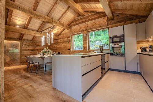 Il comprend une cuisine dotée de plafonds en bois et une salle à manger avec une table. dans l'établissement Luxury Chalet with Sauna & Jacuzzi in Megeve, à Megève