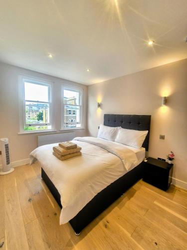 a bedroom with a large bed with two windows at Stylish Three Bedroom Ensuite Duplex Apartment in West Hampstead in London