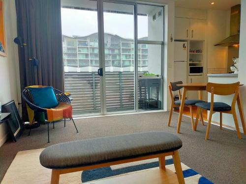 a living room with a table and chairs and a kitchen at Trendy Sunny Inner city apartment in Wellington