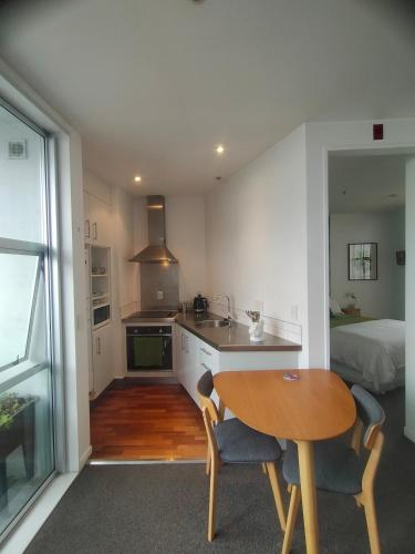 a kitchen with a table and a kitchen with a bed at Trendy Sunny Inner city apartment in Wellington