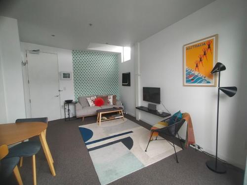 a living room with a couch and a table at Trendy Sunny Inner city apartment in Wellington