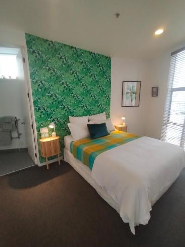 a bedroom with a large bed with a green wall at Trendy Sunny Inner city apartment in Wellington