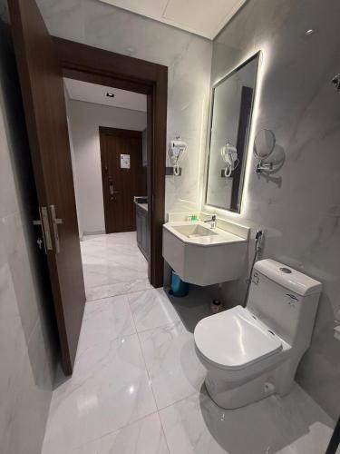 a bathroom with a white toilet and a sink at جوهرة الكروان للشقق المخدومة in Medina