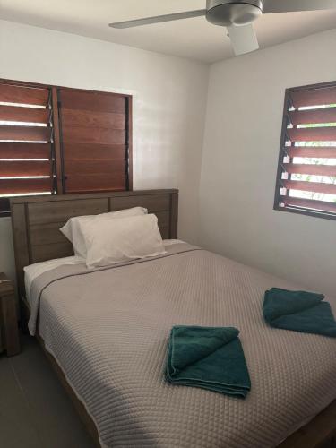 a bedroom with a bed with two green towels on it at Island Unit in Pango - Surfhouse in Port Vila