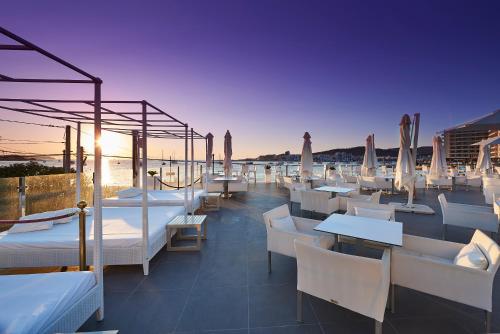 a restaurant with white tables and chairs and the ocean at Typic Marina Playa - Adults Only in San Antonio Bay