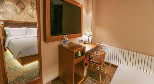 a bedroom with a bed and a desk with a television at James Joyce Coffetel Changchun People's Square in Changchun