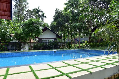 a swimming pool in front of a house at Snow white resort wayanad in Wayanad