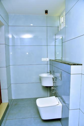 a white bathroom with a toilet and a sink at Snow white resort wayanad in Wayanad