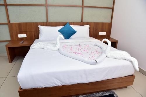 a bedroom with two beds with white sheets and blue pillows at Snow white resort wayanad in Wayanad