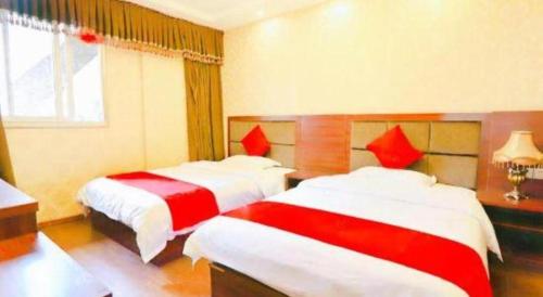 a bedroom with two beds with red and white sheets at OYO Huifeng Business Hotel in Lanzhou