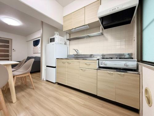 Una cocina con un refrigerador blanco y una mesa. en Residence Yu by b hotel - Relaxing 2BR Near City Center Dining & Kitchen, en Hiroshima