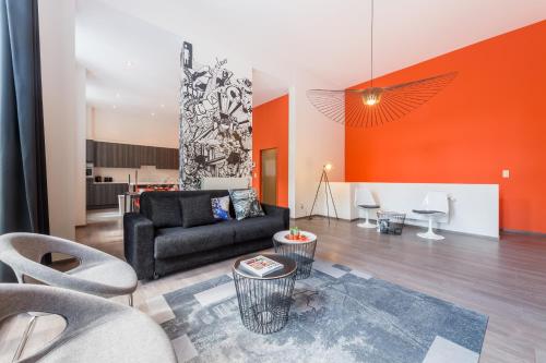 ein Wohnzimmer mit einem schwarzen Sofa und einer orangefarbenen Wand in der Unterkunft Smartflats Design - Berlaymont in Brüssel