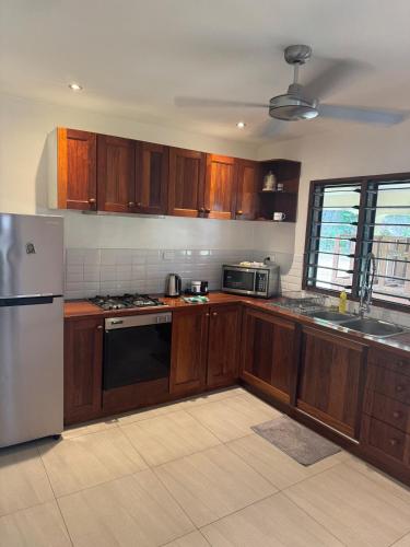 a kitchen with wooden cabinets and a white refrigerator at Island Unit in Pango - Bunkhouse in Port Vila