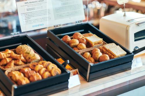 two trays of different types of bread and pastries on a counter at Park Hotel Tokyo in Tokyo