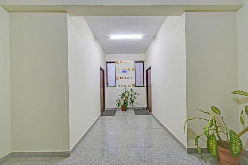 a hallway with white walls and plants at FabHotel Namaha Suites - Nr Hyderabad International Airport, Shamshabad in Hyderabad