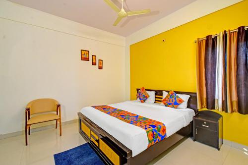 a bedroom with a bed and a chair in it at FabHotel Namaha Suites - Nr Hyderabad International Airport, Shamshabad in Hyderabad