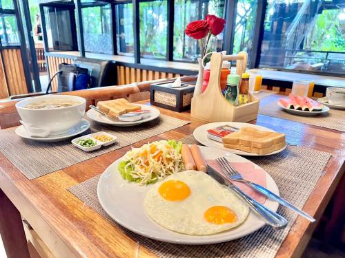 a wooden table with plates of food on it at IP Plus Pool Villa Pattaya in Jomtien Beach