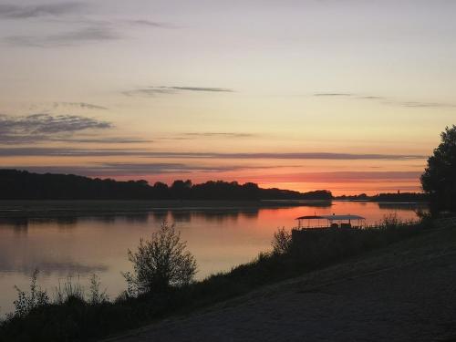 un coucher de soleil sur un lac avec un bateau dans l'eau dans l'établissement un air de vacances, à Longué