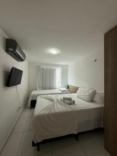 ein Hotelzimmer mit zwei Betten und einem Fernseher in der Unterkunft Israel Flat beira-mar in João Pessoa