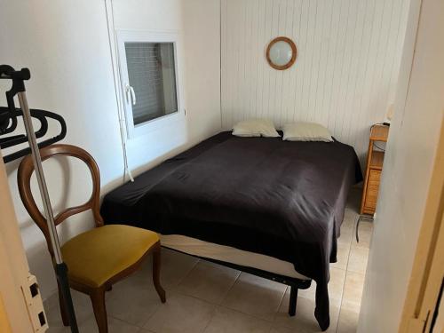 une petite chambre avec un lit et une chaise dans l'établissement Bas de Chalet à Gruissan Plage, à La Celle-sous-Gouzon