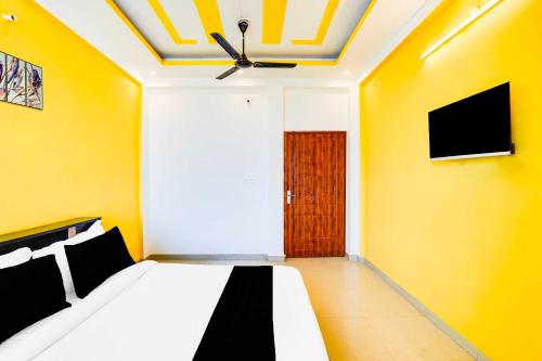 a bedroom with a bed with yellow walls and a ceiling at Collection O Kedarpuram doon university in Dehradun